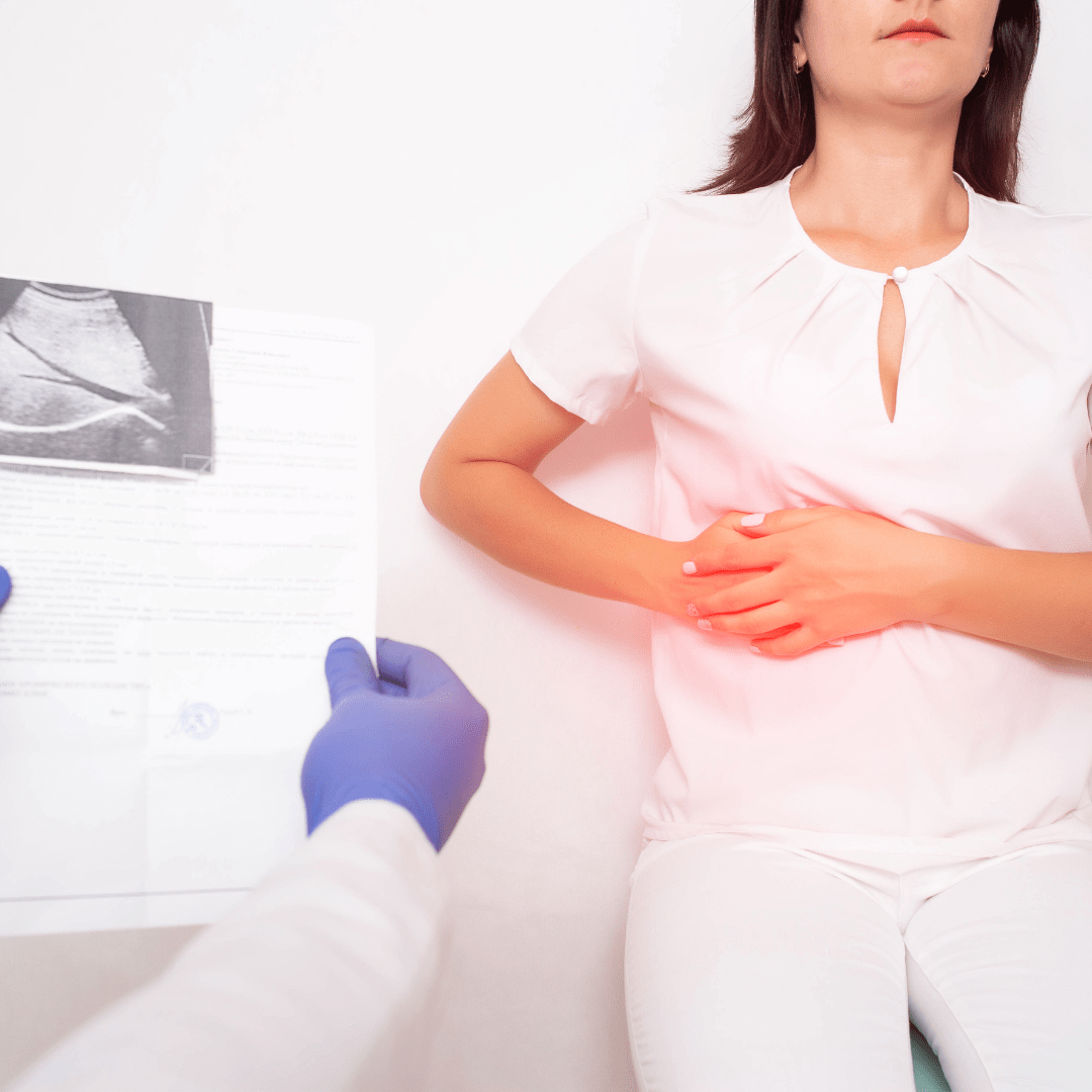 Patient holding stomach in pain while doctor reviews medical test results