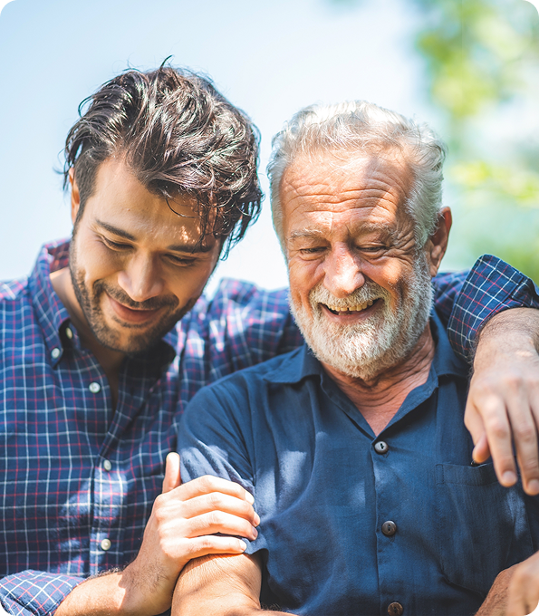 Smiling older man with gray beard walking arm in arm with younger man outdoors