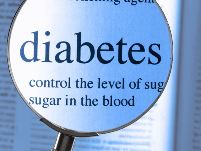 Magnifying glass highlighting the word diabetes and text about controlling blood sugar in a dictionary
