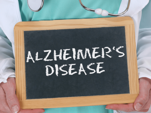 Doctor holding chalkboard with Alzheimer’s disease written on it