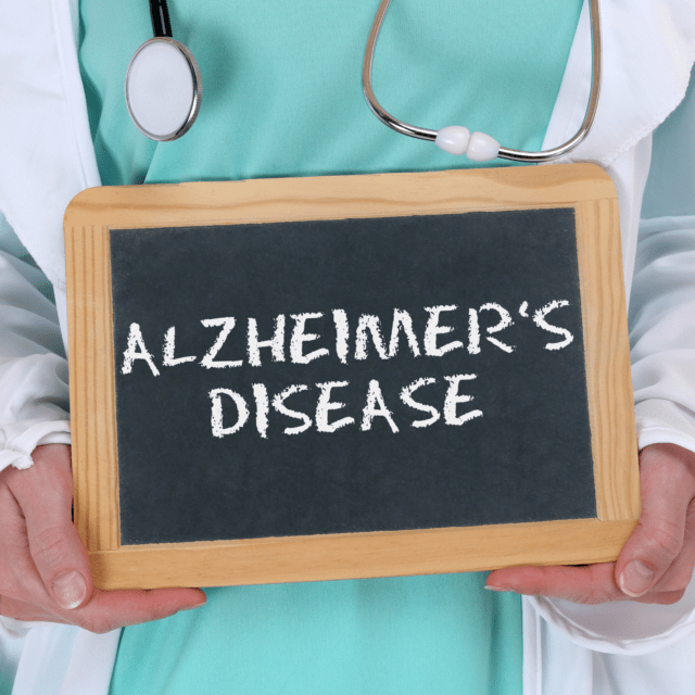 Doctor holding chalkboard with Alzheimer’s disease written on it