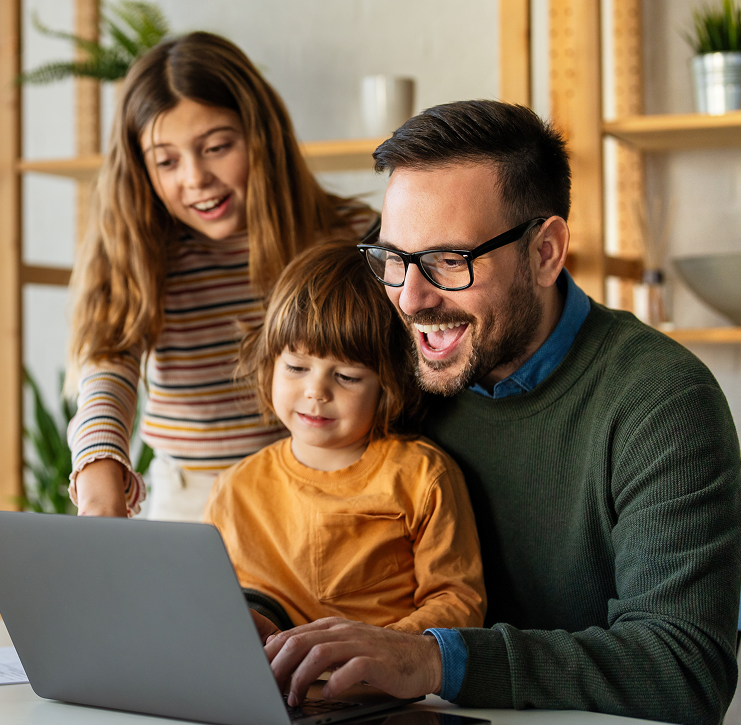 Father smiling with two children while looking at a laptop together